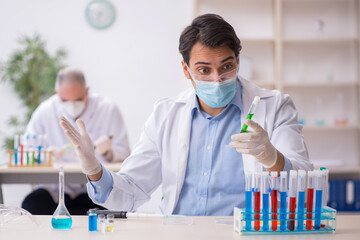 Two male chemists working at the lab during pandemic