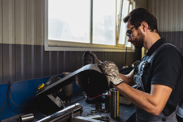 Portrait of young man, male auto mechanic in dungarees working at car service station, indoors. Concept of labor, occupation, business, caree, job