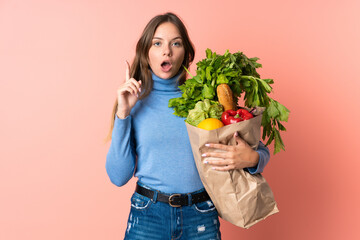 Young Lithuanian woman holding a grocery shopping bag thinking an idea pointing the finger up