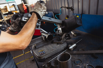 Close-up hands of male auto mechanic in dungarees with work tools working at car service station, indoors. Concept of labor, occupation, business, caree, job