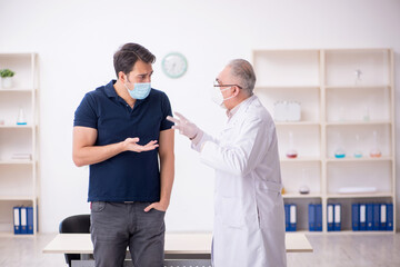 Obraz premium Young male patient visiting old male doctor during pandemic