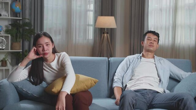 Young Asian Couple Are Watching Tv At Home With Sad Faces. Human Emotions And Television Concept
