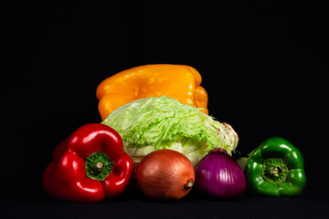 Verduras frescas, fondo negro. Pimiento, lechuga, cebolla.