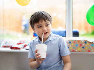 Portrait happy mixed race child boy drinking water or juice from paper cup, Cute young kid with...