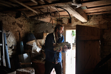Fototapeta na wymiar Poor mature man gathering firewood at home, poverty concept.