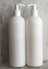 two empty white plastic containers with dispenser on a gray background. Minimalism.