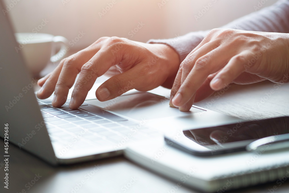 Poster close-up of man hand using and typing keyboard of laptop computer on office desk. workspace, busines
