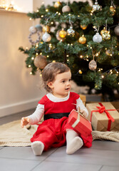 Fototapeta na wymiar christmas, holidays and childhood concept - happy baby girl opening gifts at home