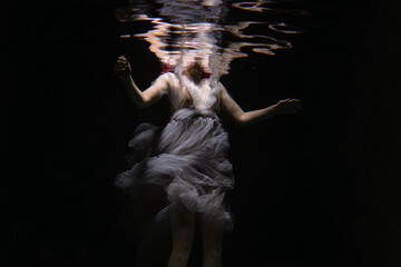 Fototapeta na wymiar Photo of a beautiful girl with red hair posing in the water. She looks like a mermaid