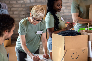Group of volunteers with working in community charity donation center.
