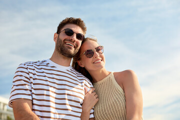 leisure, relationships and people concept - happy couple in sunglasses on summer beach