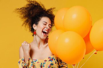 Young happy woman with culry hair in casual clothes celebrating birthday holiday party hold bunch...