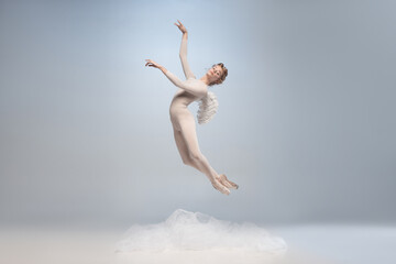 Young and graceful ballet dancer, ballerina dancing in image of angel with wings isolated on gray...