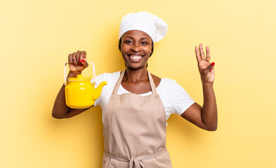 black afro chef woman smiling and looking friendly, showing number three or third with hand...