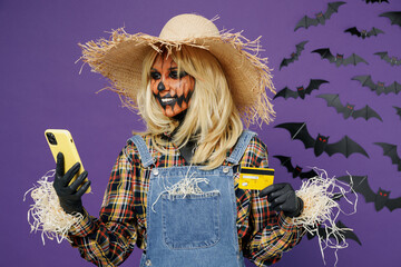 Young woman with Halloween makeup mask in straw hat costume use mobile cell phone credit bank card...