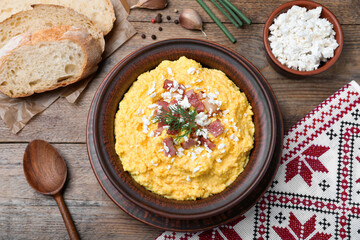 Traditional Ukrainian banosh served with brynza and pork cracklings on wooden table, flat lay