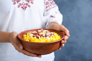 Woman holding bowl of banosh with brynza and pork cracklings on blue background, closeup....