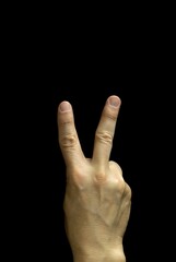 A male hand making the victory sign with his fingers, arranged in the letter V, black background