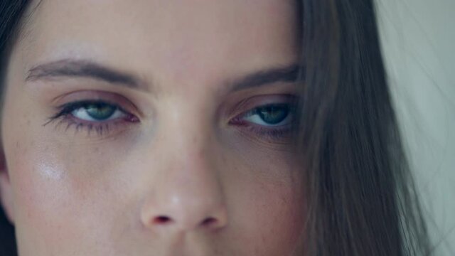 Close-up of blue eyes of a Caucasian girl. Serious beautiful girl blinks a slow-moving video.
