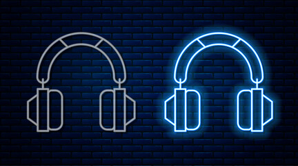 Glowing neon line Headphones icon isolated on brick wall background. Earphones. Concept for listening to music, service, communication and operator. Vector