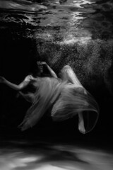 Black and white photographs where a beautiful girl poses in the water. She looks like a mythical mermaid