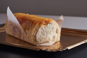 View of delicious roulade or swiss roll filled with cream on a golden tray. Delicious gypsy arm dessert.