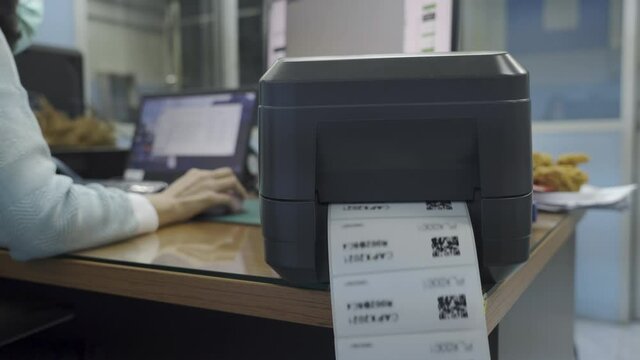 The black barcode printer is printing the QR code on the sticker.