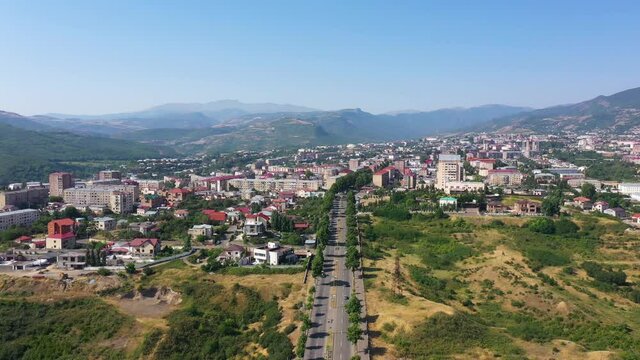Aerial view famous monument in Stepanakert city, Artsakh, Armenia. Drone slowly move to famous statute grandfather and grandmother in Nagorno-Karabakh (Artsakh) region. Tourists near statue.