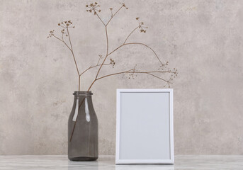 Empty picture frame and vase with dry flowers . Minimalist style home interior decoration. Simple and elegant design. Copy space image.