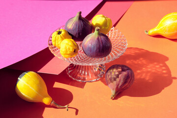Autumn colors. Purple fig, yellow quince fruits on vibrant red, orange, magenta, fuchsia layered...