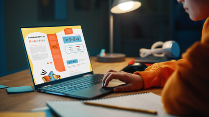 Smart Young Boy Researching Homework Topic from an Exercise Book on Laptop Computer. Happy Teenager...