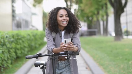 Young woman using smartphone in a city. Smiling student girl with bicycle looking at mobile phone. Modern lifestyle, connection, travel, business, mobile apps concept - Powered by Adobe