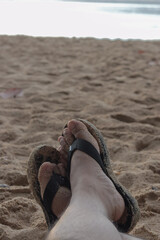 picture of a pair of feet wearing sandals on the beach sand