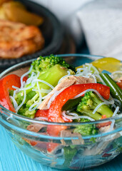 Sauteed vegetable salad with broccoli, asparagus, sweet pepper and cellophane noodles or fensi noodles in a glass bowl