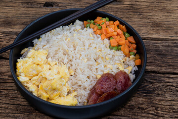 vegetable fried rice with sausage egg carrot bean isolated on wood background.
