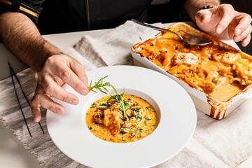 Authentic Spanish paella with cod and mussels. Traditional Mediterranean seafood dish. The chef decorates the dish with herbs. Restaurant dish serving. Close-up. People at work. Body parts