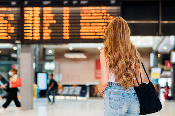 Young caucasian woman checking departures watching board waiting