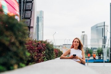 Young caucasian woman using smartphone looking camera positive and trustful in future