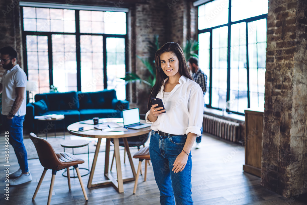 Aufkleber half length portrait of pretty caucasian blogger with modern cellphone gadget in hand looking at cam
