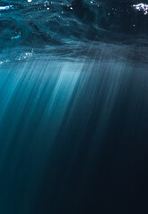 Sun rays of lights underwater in to blue clear ocean and bubbles