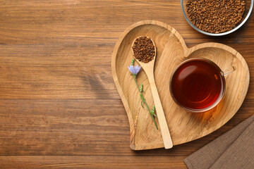 Cup of delicious chicory drink, granules and flower on wooden table, flat lay. Space for text