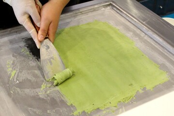 Cooking of green sweet stir-fried ice cream, also known as rolled ice cream, a Thai frozen dessert with sugar and matcha, an exotic food and a popular treat.