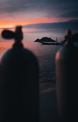 sunset on the beach after scuba dives showing tanks on shore and boat on background