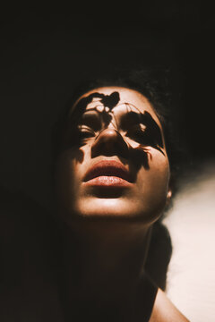 Model with leaf shadows on face in light ray