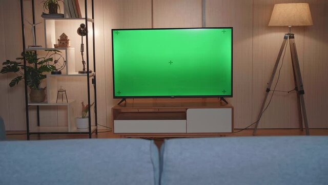 Shot Of A Tv With Horizontal Green Screen Mock Up. Cozy Evening Living Room At Home
