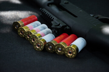 Shotgun, shotgun cartridges on a black leather background - obrazy, fototapety, plakaty