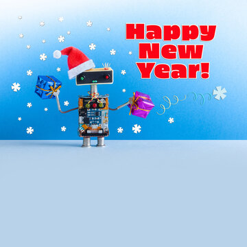 Santa Claus robot holds boxes of gifts, wishes a Happy New Year. Festive Christmas card with a kind toy robot on a snowy blue background with free space for text.