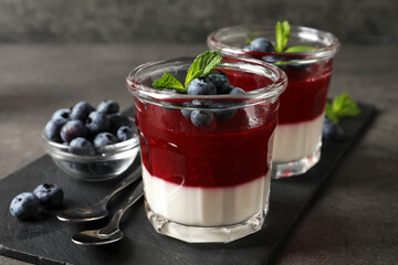 Delicious panna cotta with fruit coulis and fresh blueberries served on grey table