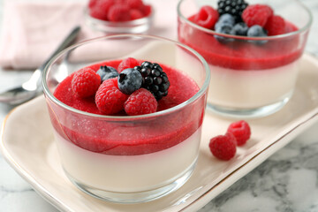 Delicious panna cotta with fruit coulis and fresh berries served on white marble table, closeup