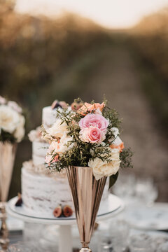 Vertical closeup of a golden vase with a small bouquet of pink roses.
